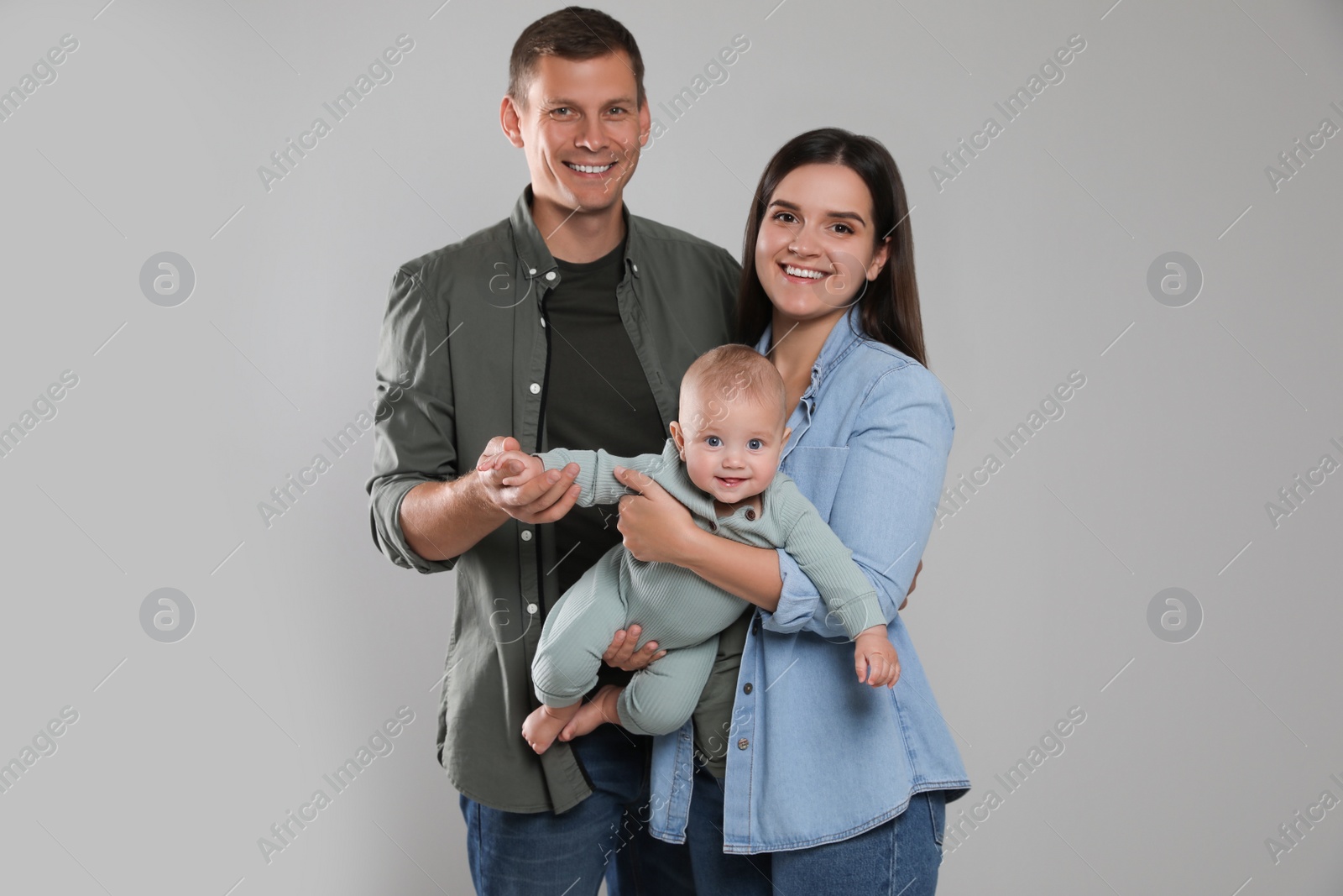 Photo of Happy family. Couple with their cute baby on grey background