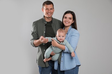 Photo of Happy family. Couple with their cute baby on grey background
