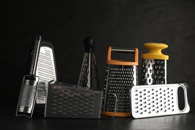 Photo of Different stainless steel graters on black table