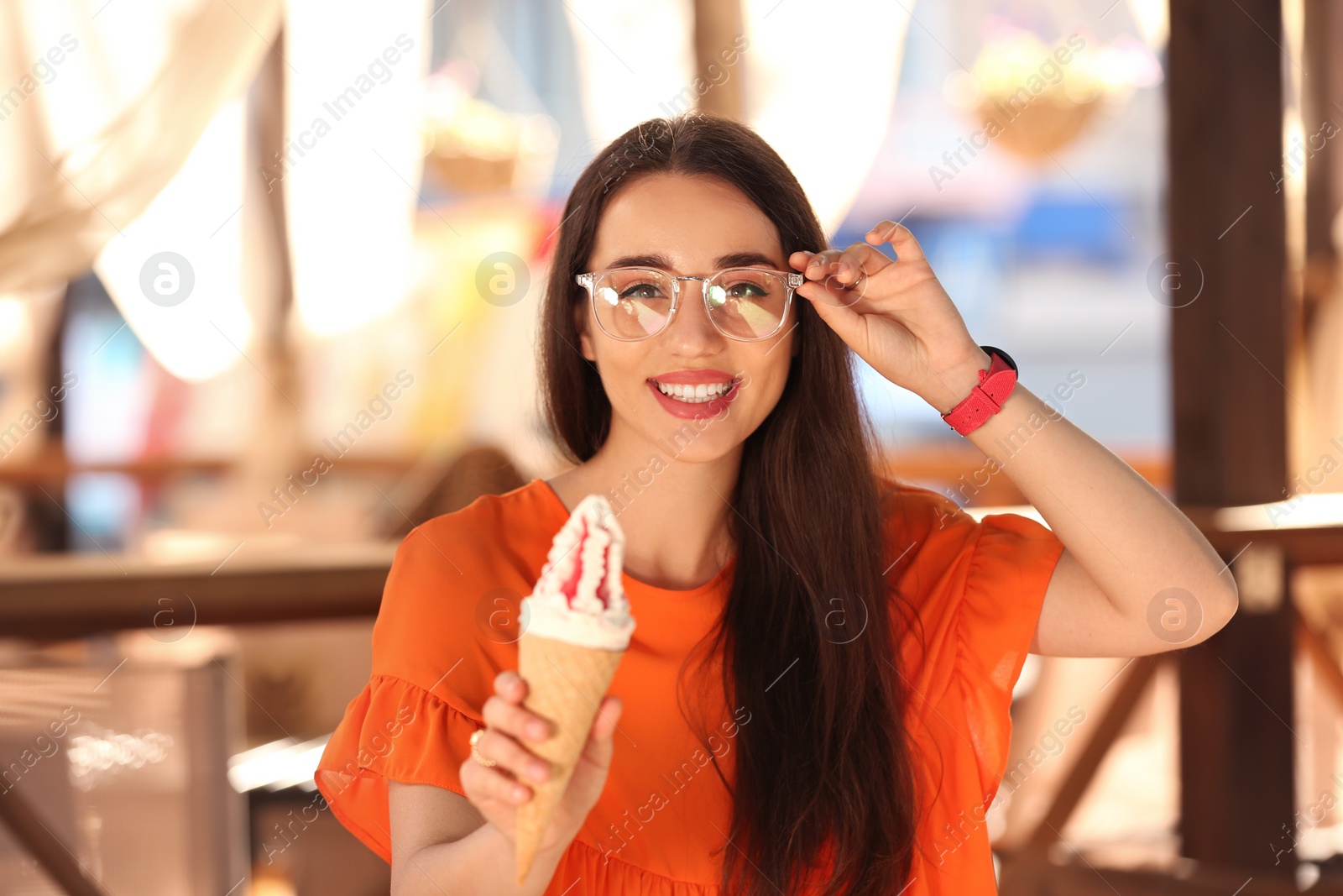 Photo of Happy young woman with delicious ice cream in waffle cone outdoors