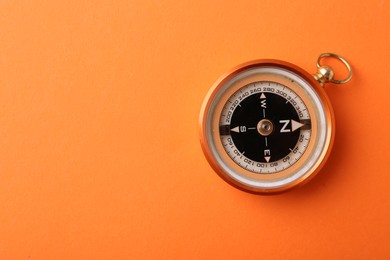 Photo of One compass on orange background, top view. Space for text