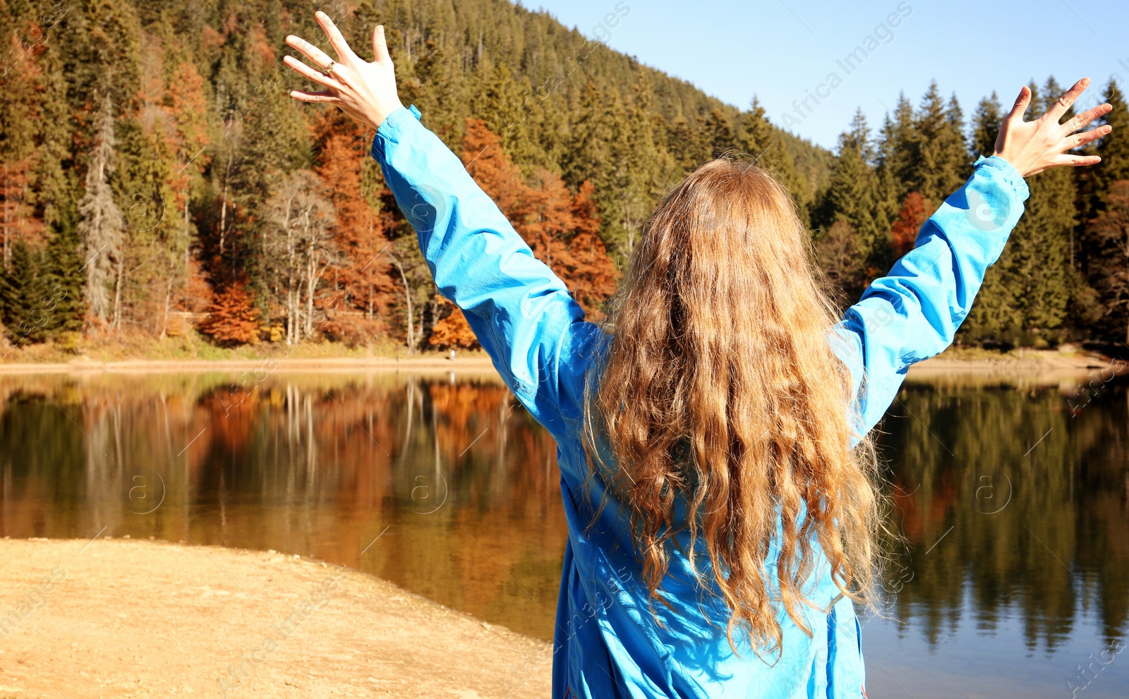 Photo of Woman enjoying view of autumn forest near lake