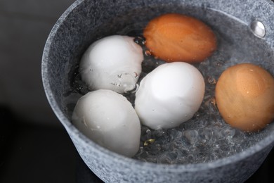 Chicken eggs boiling in saucepan on electric stove, closeup