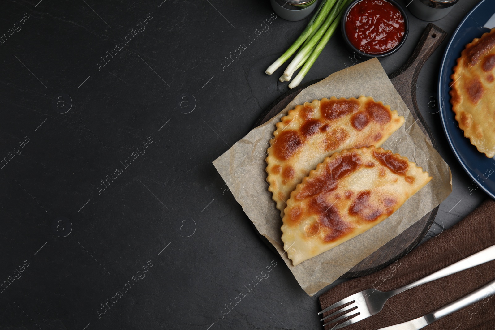 Photo of Delicious fried chebureki served on black table, flat lay. Space for text