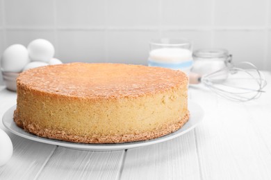 Plate with delicious sponge cake on white wooden table, space for text