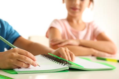 Little boy and girl doing homework at table indoors, closeup