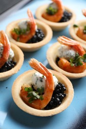 Delicious canapes with shrimps and black caviar on plate, closeup