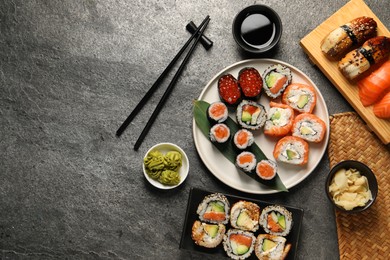 Photo of Flat lay composition with delicious sushi rolls on dark grey table. Space for text