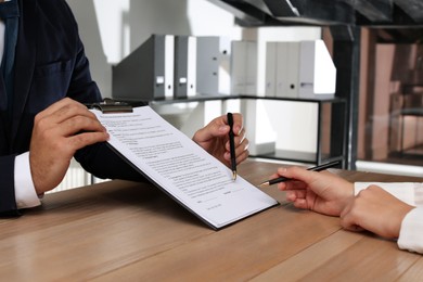 Photo of People working with Real Estate Purchase And Sale Contract at wooden table indoors, closeup