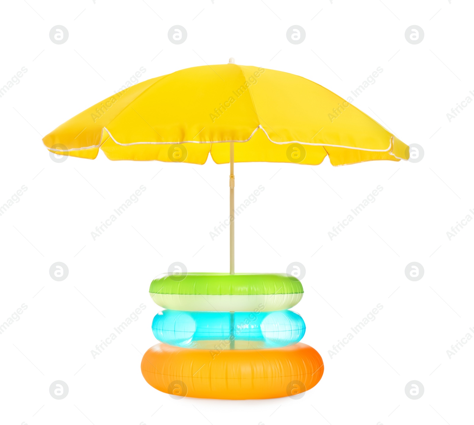 Photo of Open yellow beach umbrella with different inflatable rings on white background