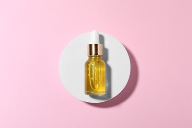 Bottle of cosmetic oil on pink background, top view