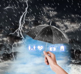 Image of Insurance agent covering illustrations with black umbrella during thunderstorm, closeup