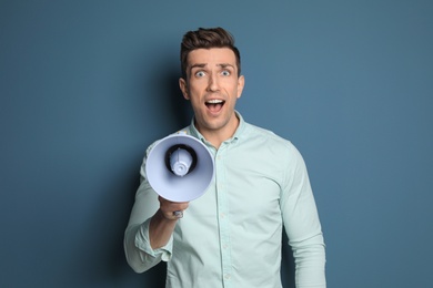 Photo of Young man with megaphone on color background