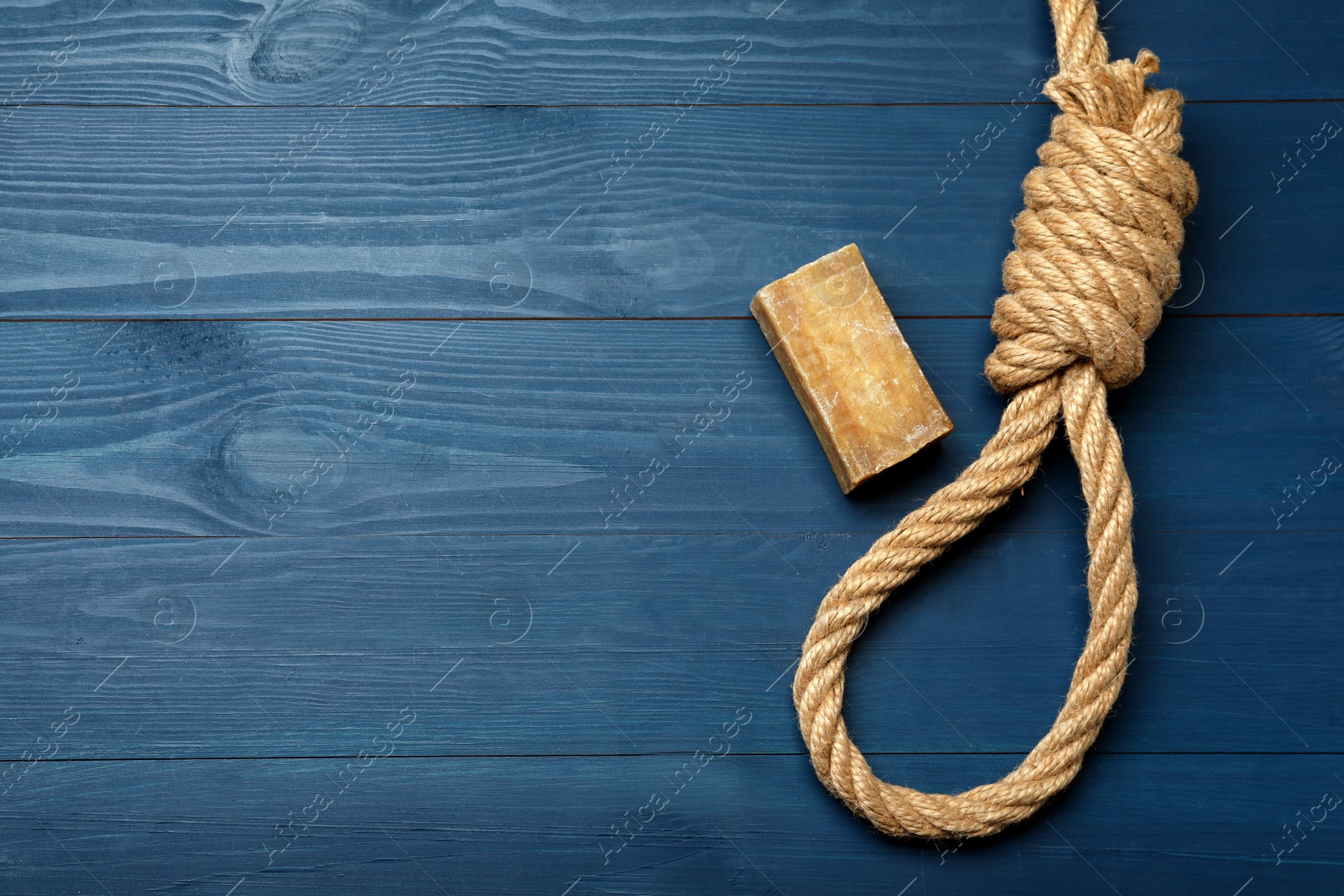 Photo of Rope noose and soap bar on blue wooden table, flat lay. Space for text