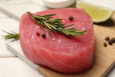 Raw tuna fillet with rosemary and spices on white table, closeup
