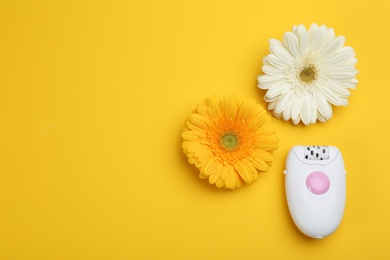 Image of Modern epilator and flowers on yellow background, flat lay. Space for text