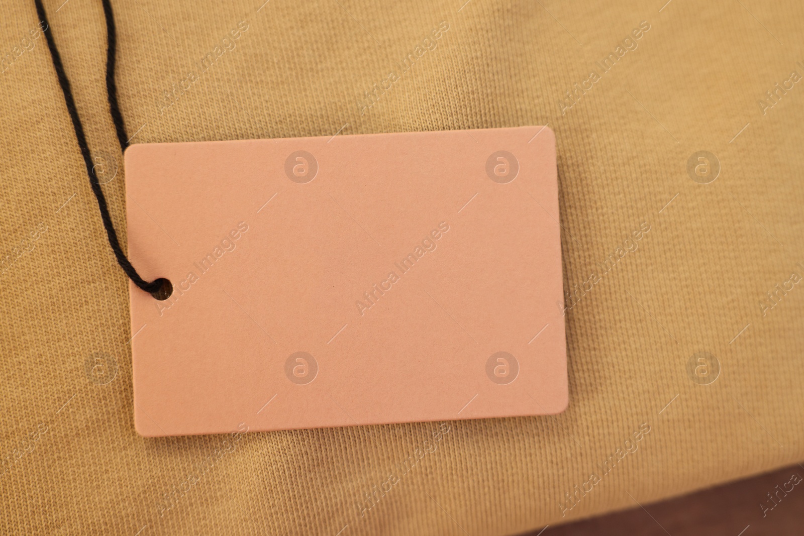 Photo of Cardboard tag on garment, closeup. Space for text