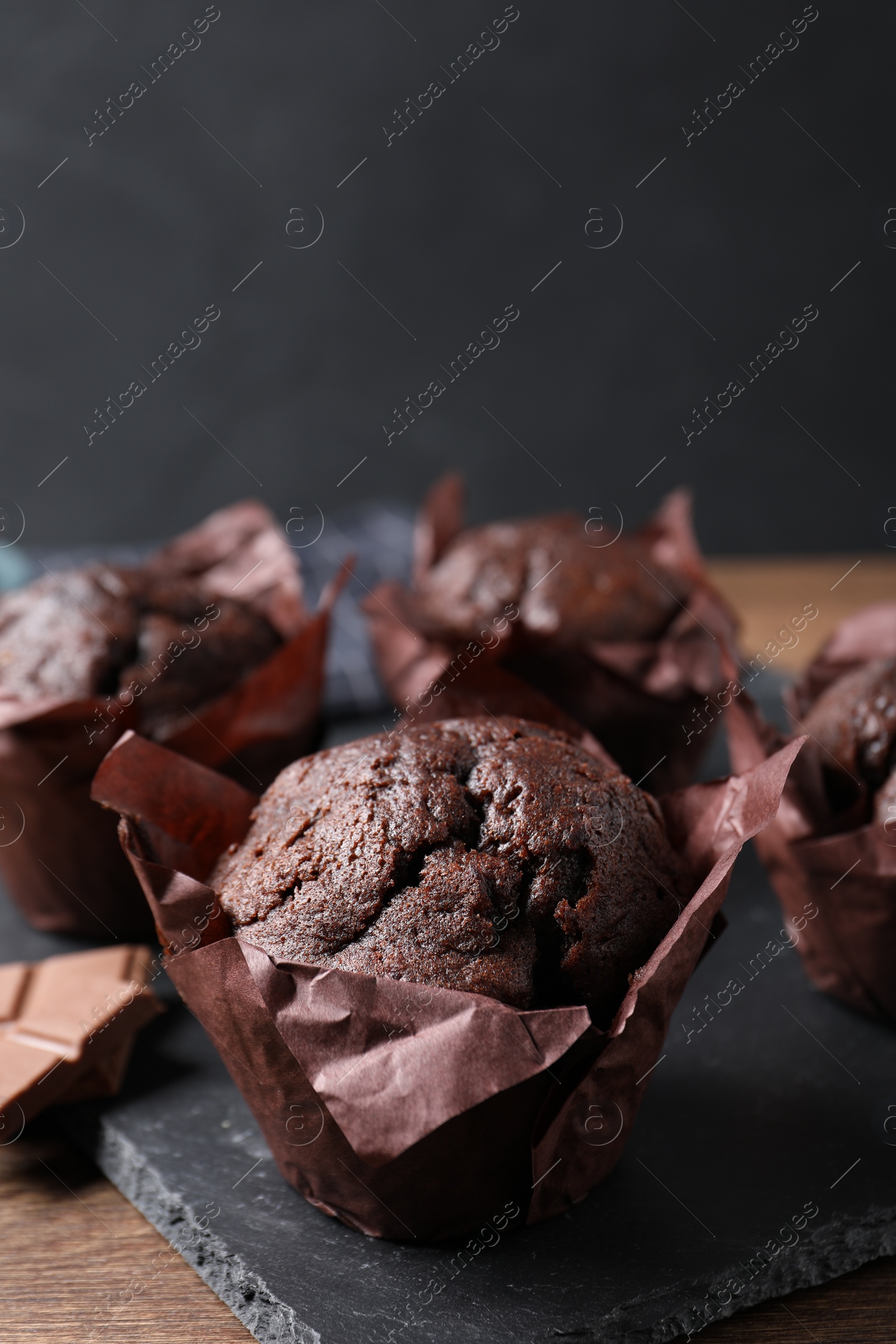 Photo of Tasty chocolate muffins on wooden table, closeup. Space for text