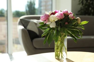 Photo of Vase with bouquet of beautiful peonies on table in room, space for text