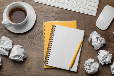 Flat lay composition with empty notebook and crumpled paper balls on wooden table. Space for text