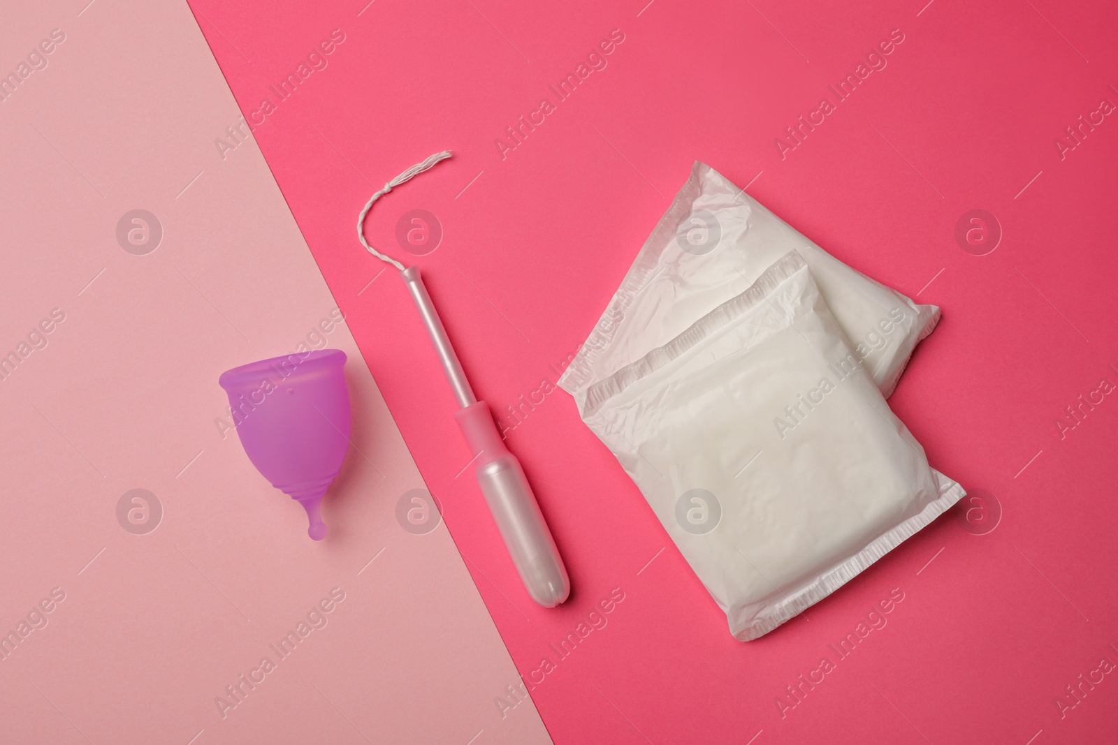 Photo of Menstrual cup, pads and tampon on color background, flat lay