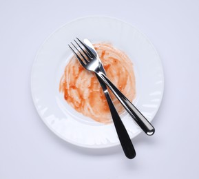 Dirty plate and cutlery on white background, top view