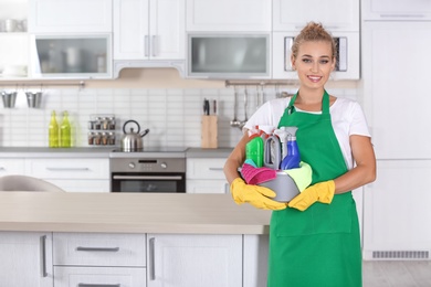 Woman with basin and cleaning supplies in kitchen