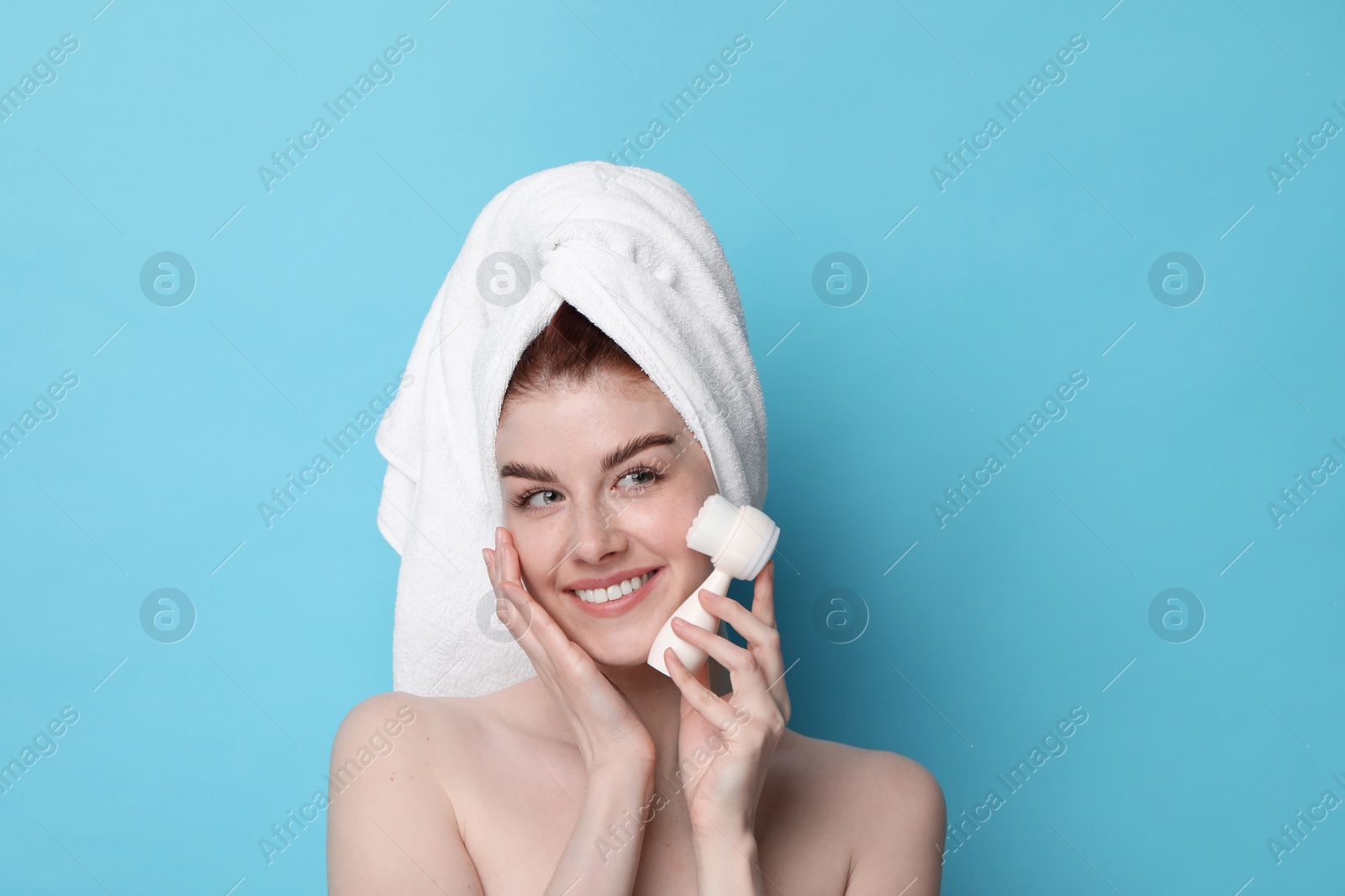 Photo of Washing face. Young woman with cleansing brush on light blue background, space for text