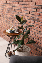 Photo of Stylish room interior with beautiful plant and side table near brick wall