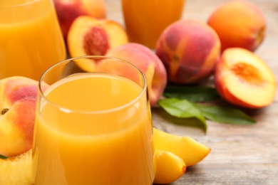 Photo of Natural peach juice and fresh fruits on wooden table, closeup