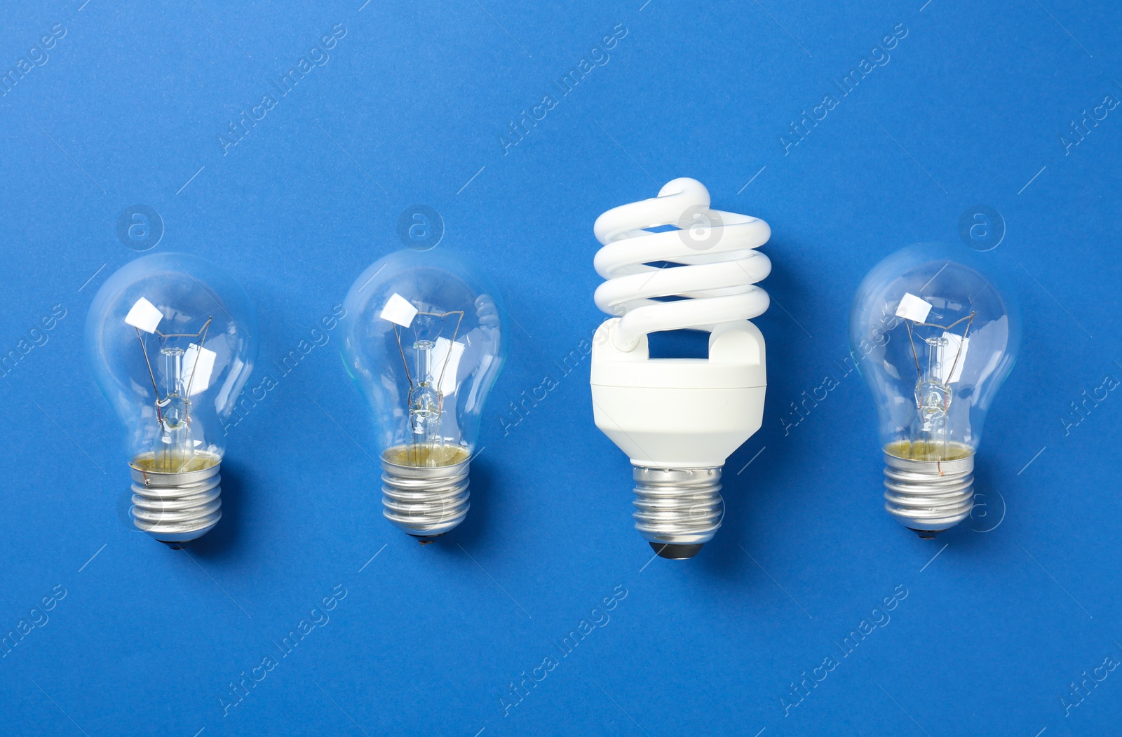 Photo of Vintage and modern lightbulbs on blue background, flat lay