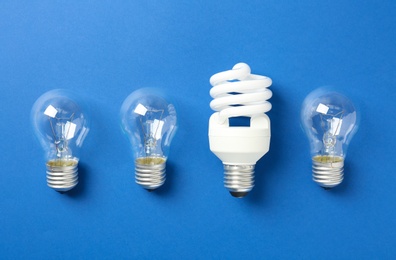 Photo of Vintage and modern lightbulbs on blue background, flat lay