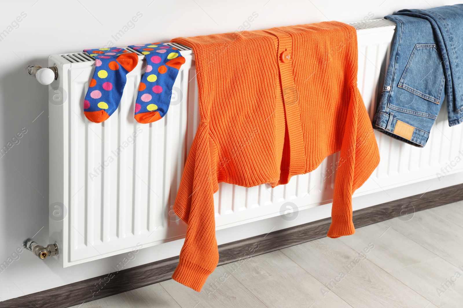 Photo of Clean clothes hanging on white radiator in room