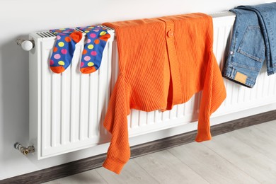 Clean clothes hanging on white radiator in room