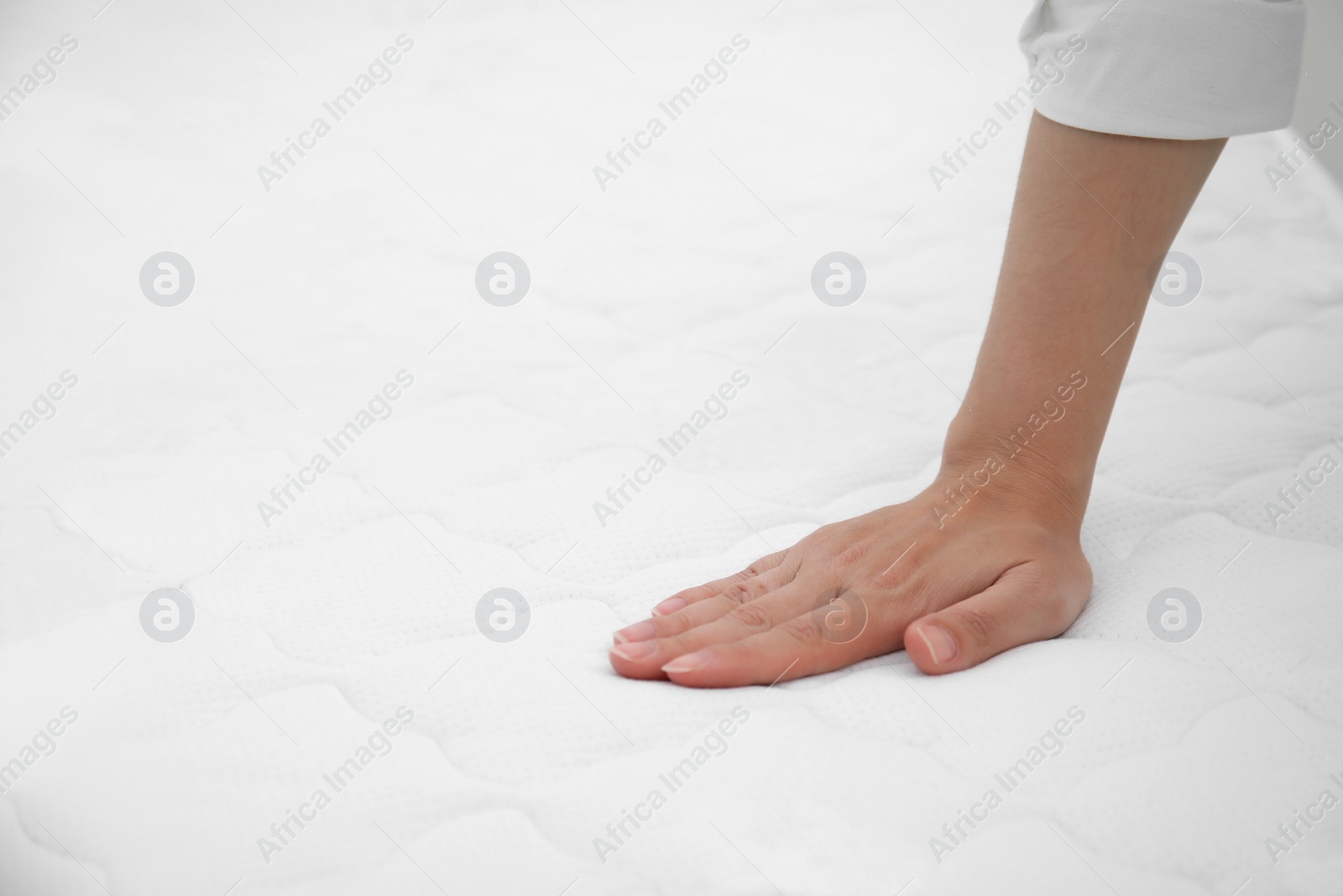 Photo of Woman touching soft white mattress, closeup. Space for text