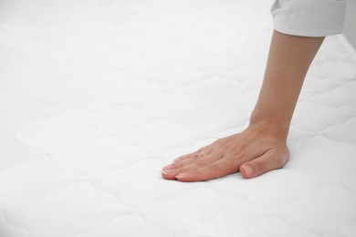 Photo of Woman touching soft white mattress, closeup. Space for text