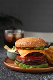 Photo of Tasty cheeseburger with patties, sauce and French fries on grey textured table, closeup