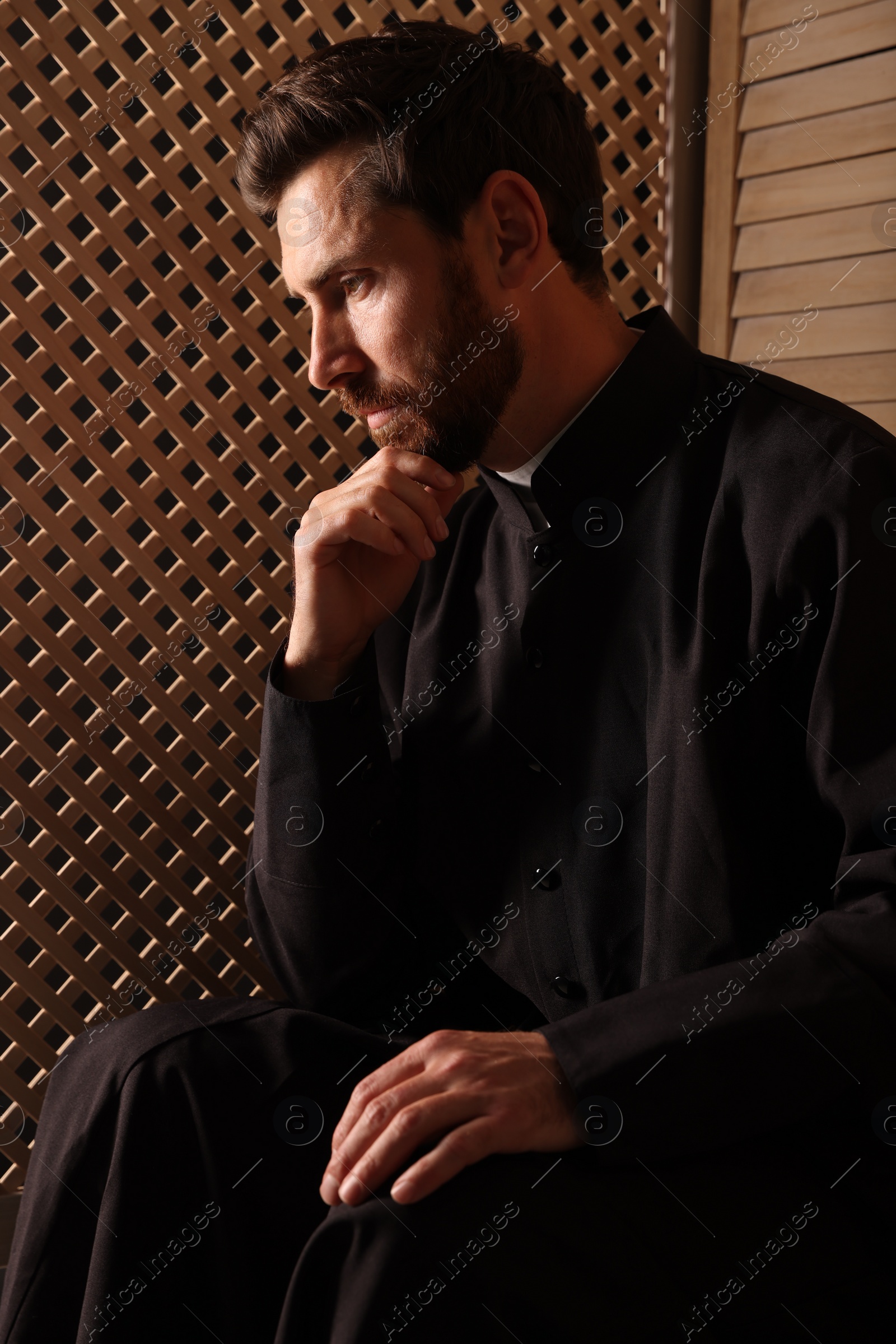 Photo of Catholic priest in cassock listening to confession