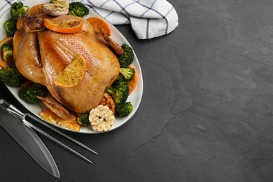 Photo of Delicious chicken with oranges and vegetables on black table, flat lay. Space for text