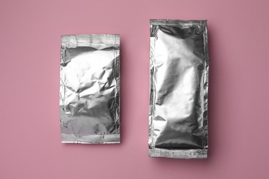 Photo of Blank foil packages on pink background, flat lay