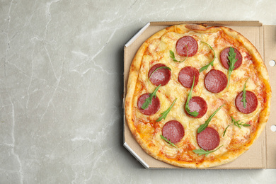 Tasty pepperoni pizza in cardboard box on light grey marble table, top view. Space for text