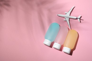 Photo of Cosmetic travel kit and toy plane on pink background, flat lay with space for text. Bath accessories
