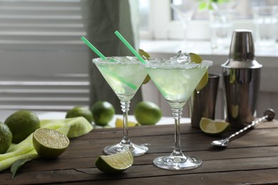 Delicious Margarita cocktail in glasses and lime on wooden table