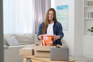 Happy woman unpacking parcel at home. Online store