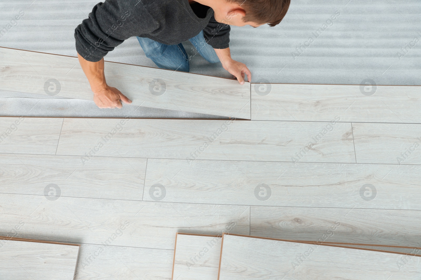 Photo of Worker installing new laminate flooring in room, above view