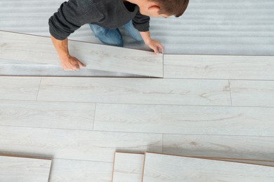 Photo of Worker installing new laminate flooring in room, above view