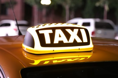 Photo of Taxi car with yellow sign on city street at night, closeup