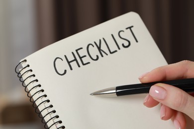 Photo of Woman filling Checklist with pen indoors, closeup