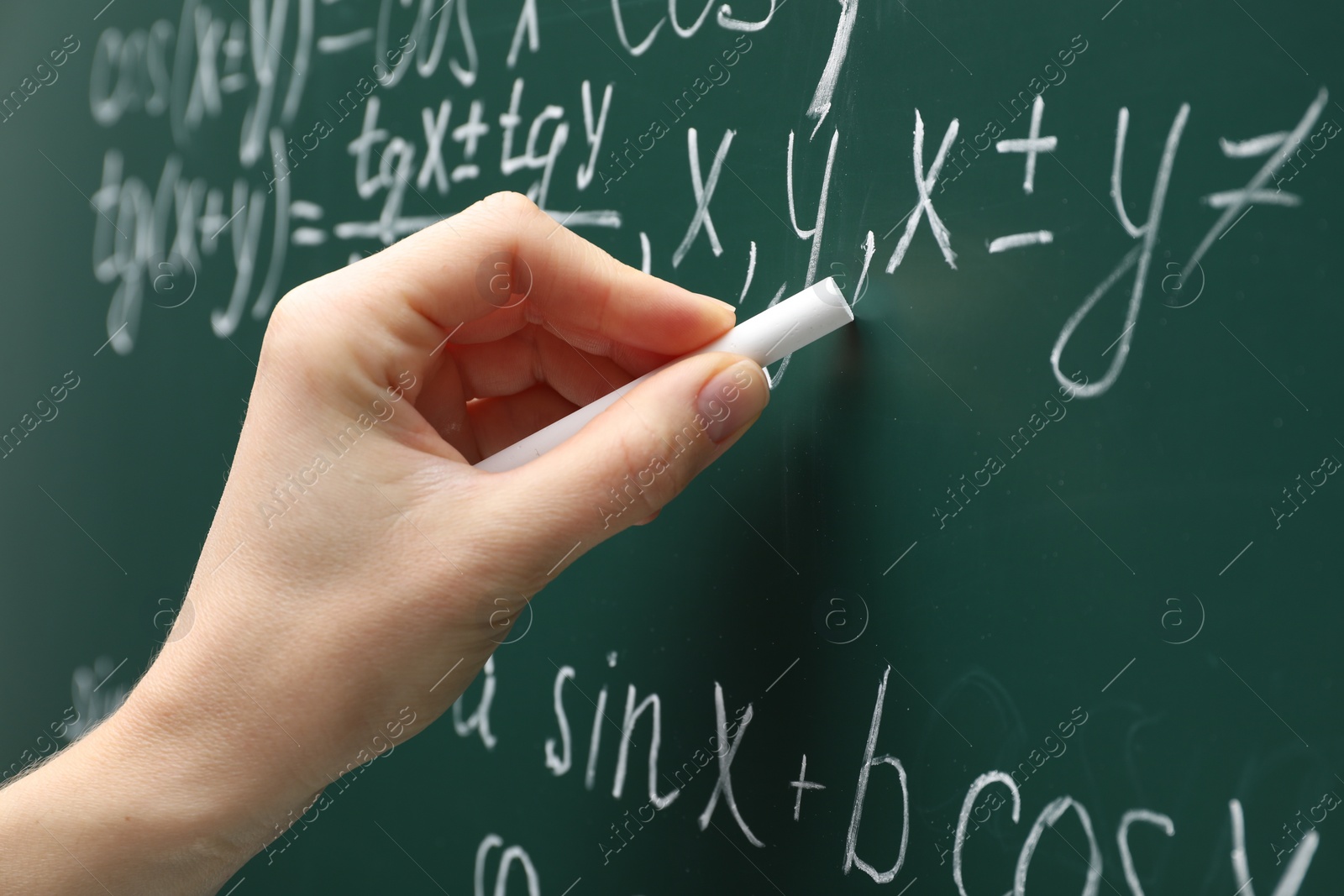 Photo of Teacher writing down math equation on green board, closeup