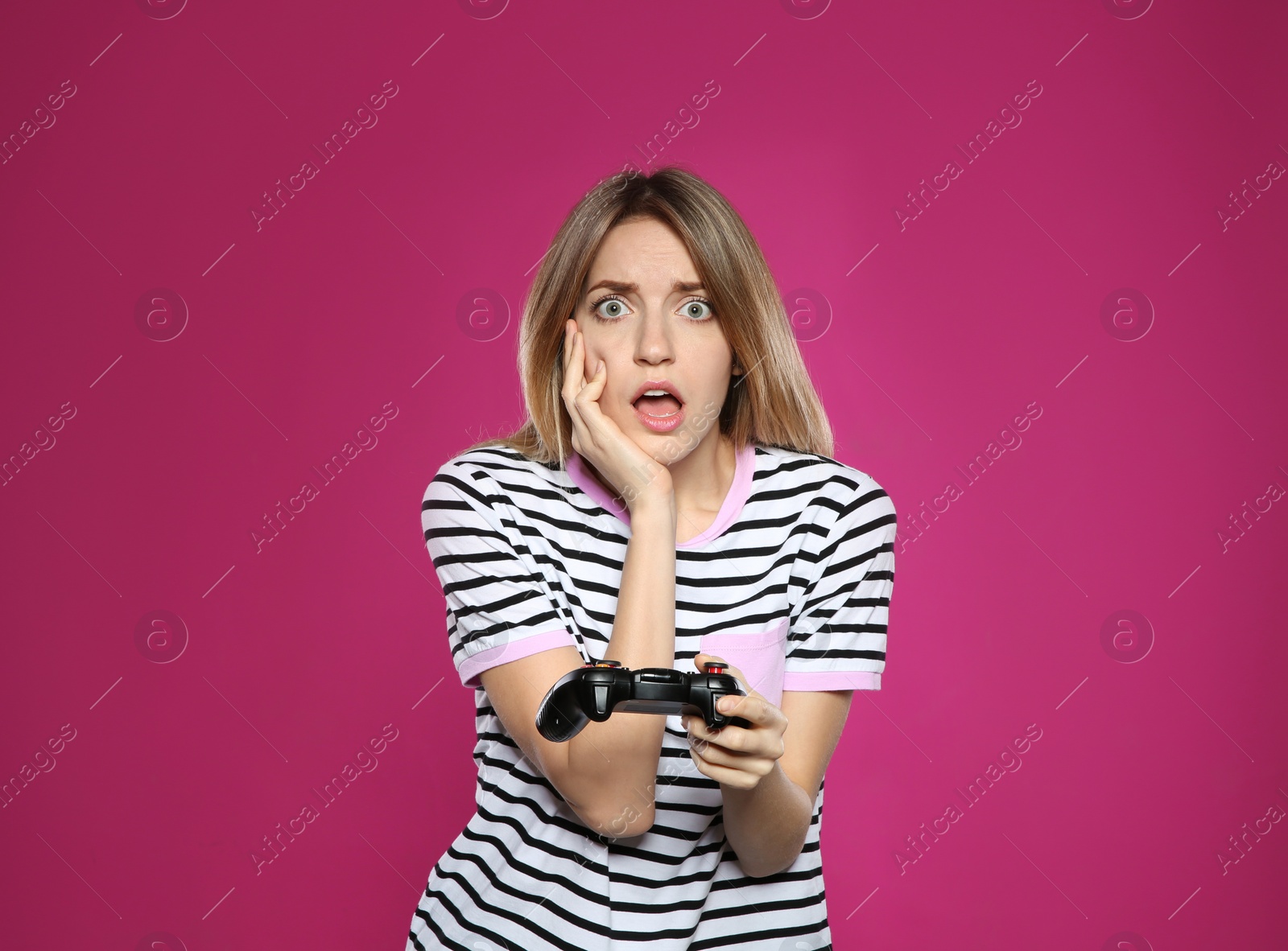 Photo of Emotional young woman playing video games with controller on color background